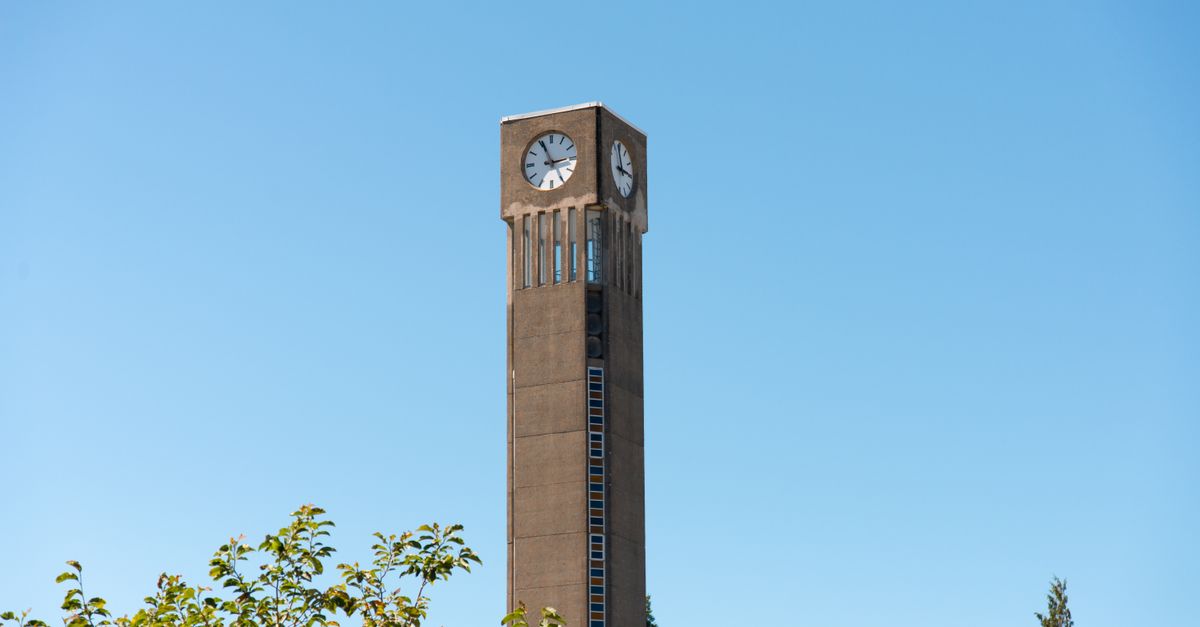 A tall clock tower stands against a clear blue sky on the UBC Vancouver campus.